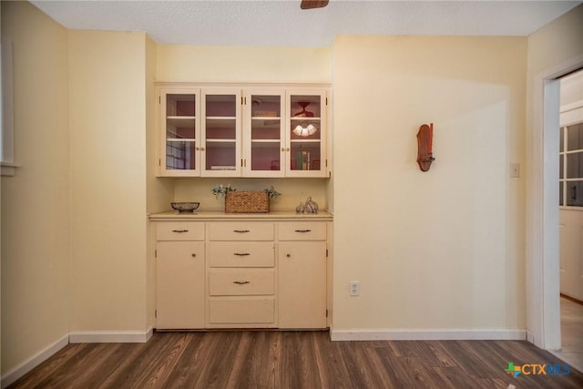 interior space featuring a textured ceiling, dark wood-type flooring, and baseboards