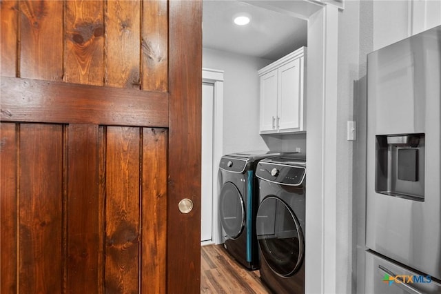 washroom with wood finished floors, washing machine and dryer, and cabinet space