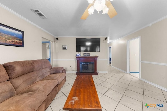 living room with visible vents, a ceiling fan, light tile patterned flooring, crown molding, and a glass covered fireplace