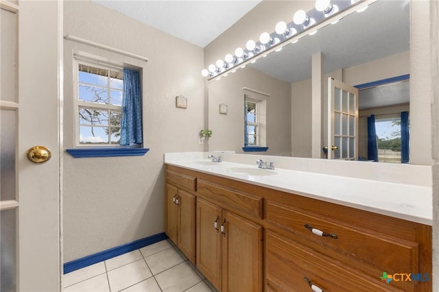 bathroom featuring double vanity, tile patterned floors, baseboards, and a sink