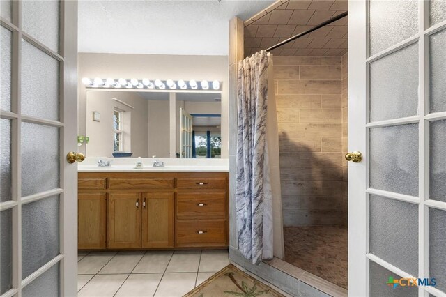 full bath featuring tile patterned floors, vanity, and a tile shower