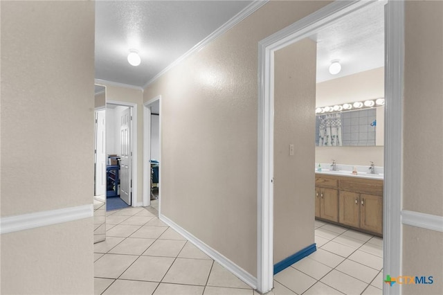 hall featuring a sink, ornamental molding, and light tile patterned flooring