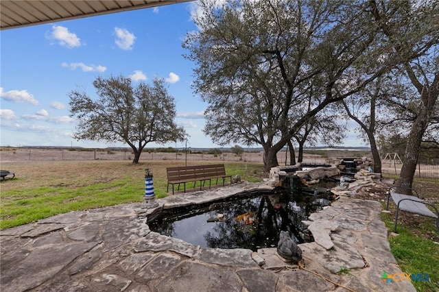 view of yard with fence and a small pond