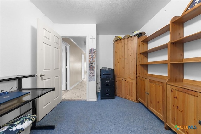 unfurnished office with light colored carpet, a textured ceiling, and light tile patterned floors