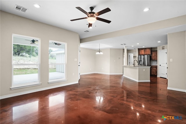 unfurnished living room featuring sink and ceiling fan with notable chandelier