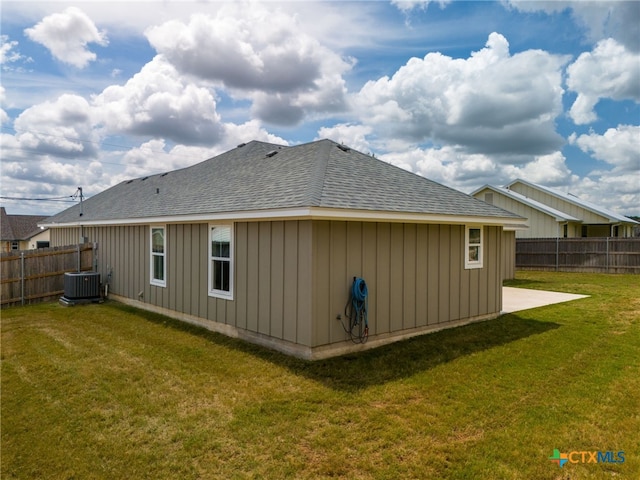 back of house featuring central AC unit and a lawn