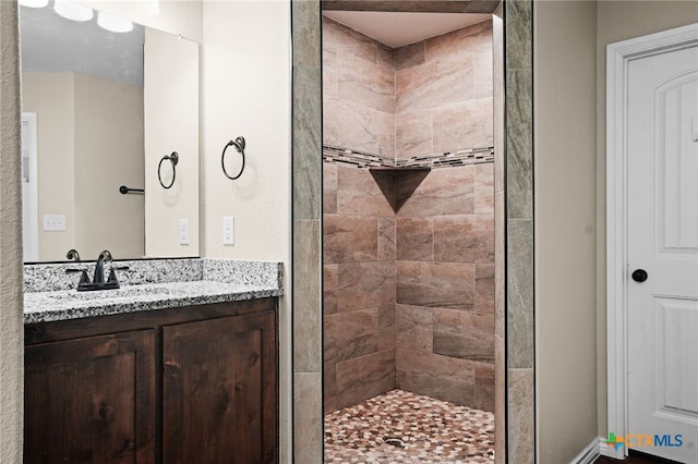 bathroom with tiled shower and vanity