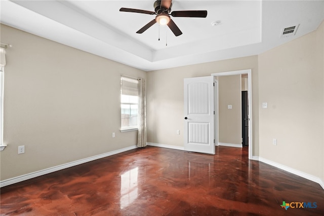 empty room featuring ceiling fan and a raised ceiling