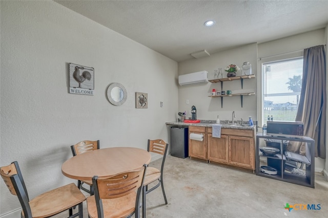 kitchen with a textured ceiling, light colored carpet, stainless steel dishwasher, and a wall mounted air conditioner