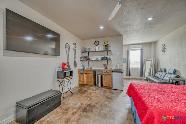 interior space featuring concrete flooring, appliances with stainless steel finishes, a textured ceiling, and ceiling fan