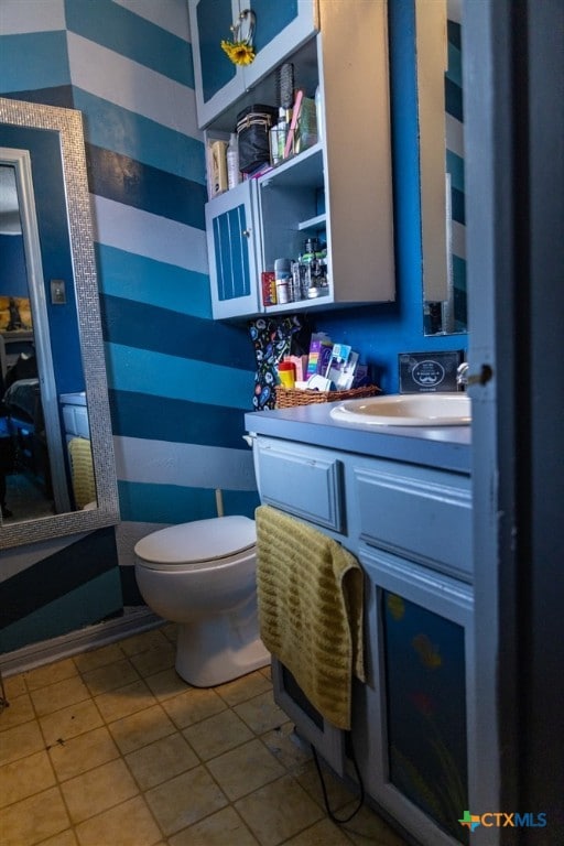 half bathroom featuring vanity, toilet, and tile patterned floors