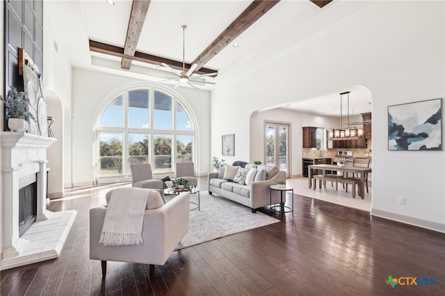 living room with a tile fireplace, a high ceiling, and dark hardwood / wood-style floors