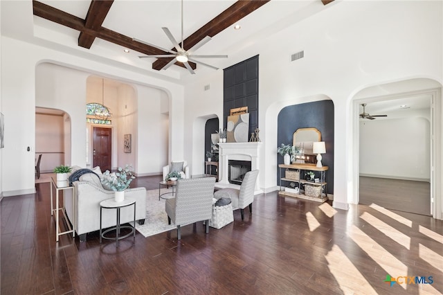 living room with beamed ceiling, dark hardwood / wood-style floors, a high ceiling, and an inviting chandelier