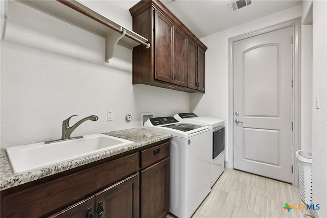 laundry room with washer and clothes dryer, cabinets, sink, and a textured ceiling