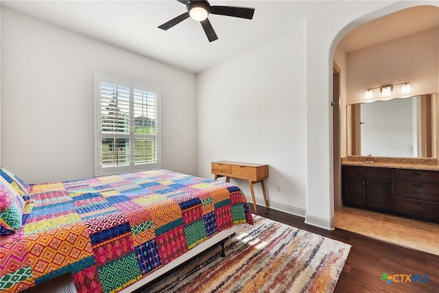 bedroom featuring dark hardwood / wood-style floors, ceiling fan, sink, and connected bathroom