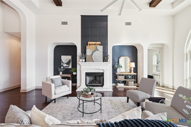 living room with beam ceiling, dark wood-type flooring, and a high ceiling