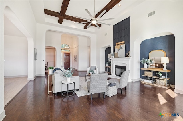 living room with beam ceiling, a towering ceiling, dark hardwood / wood-style floors, and ceiling fan