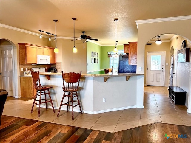 kitchen with black refrigerator, pendant lighting, a breakfast bar, and backsplash