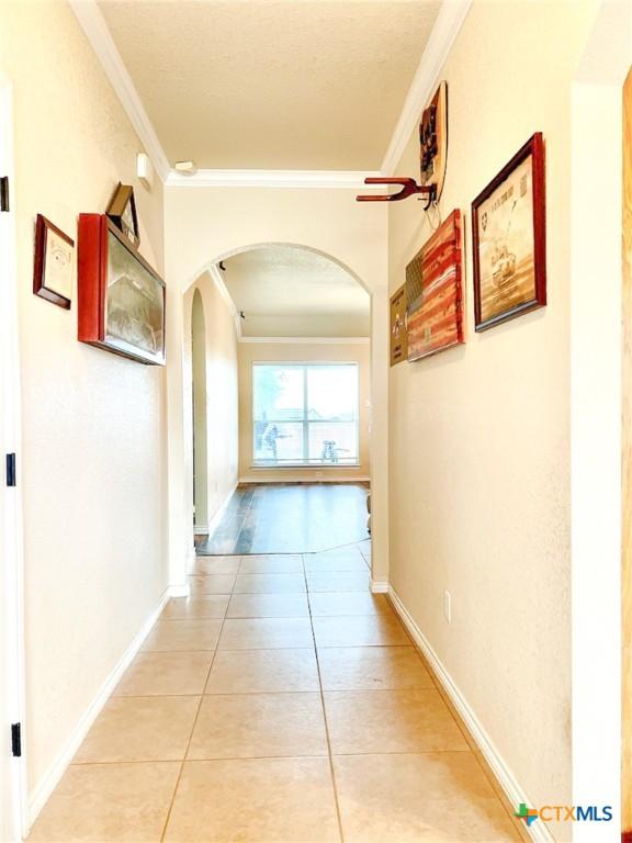 corridor featuring light tile patterned flooring and ornamental molding