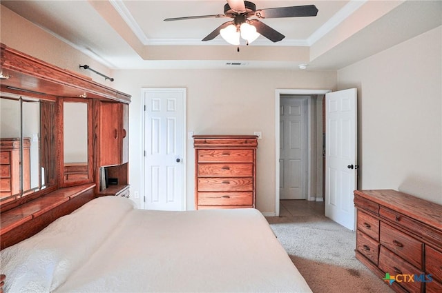 carpeted bedroom with a tray ceiling and ornamental molding