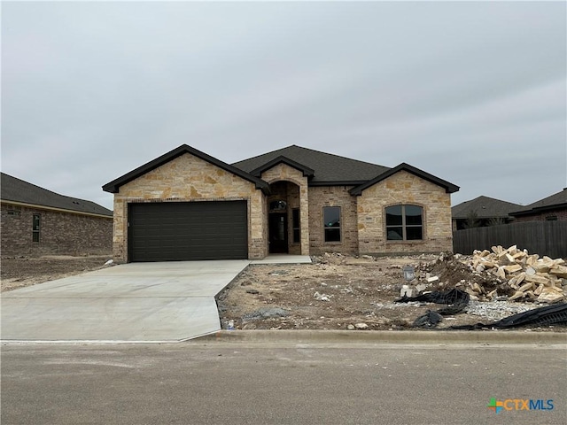 view of front of house with a garage, concrete driveway, and fence