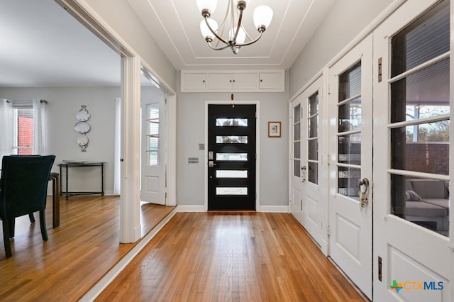 foyer featuring an inviting chandelier, wood-type flooring, and a healthy amount of sunlight