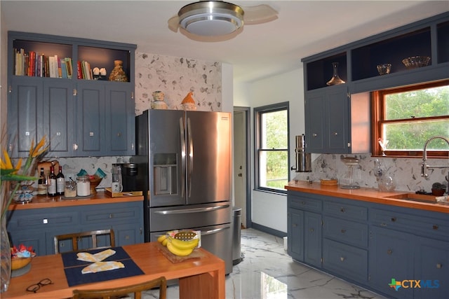 kitchen featuring blue cabinetry, stainless steel fridge with ice dispenser, and a healthy amount of sunlight