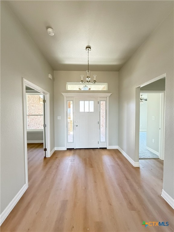 entryway featuring a notable chandelier, light wood-type flooring, and baseboards