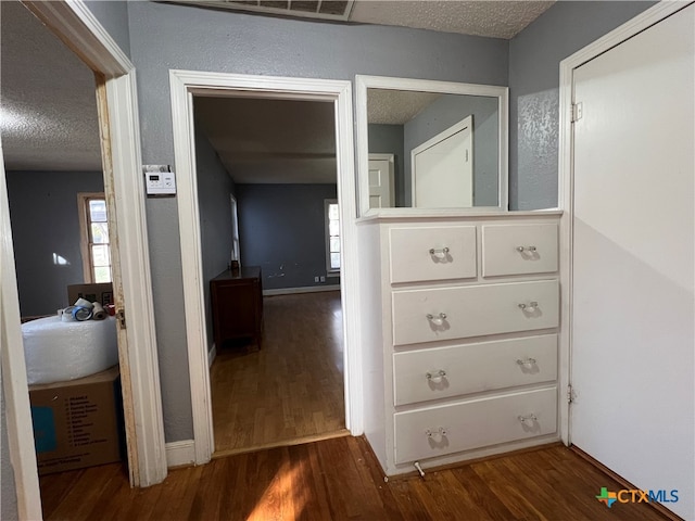 corridor with dark hardwood / wood-style flooring and a textured ceiling