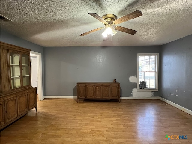 unfurnished room with ceiling fan, a textured ceiling, and light hardwood / wood-style flooring