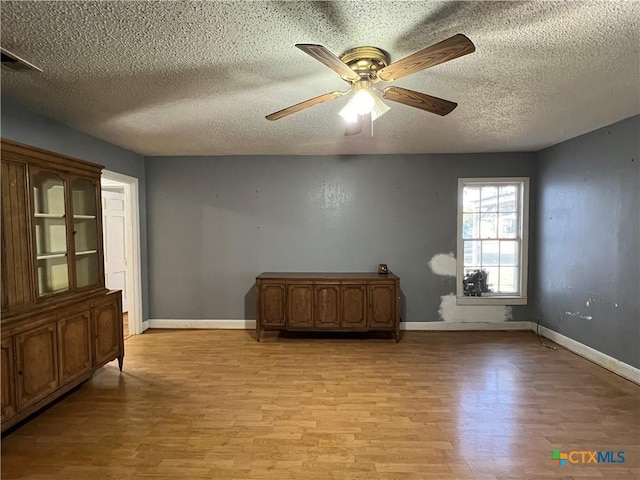 1215 S 47th St, Temple, TX 76504 - spare room with light wood-style flooring, a textured ceiling, ceiling fan, and baseboards