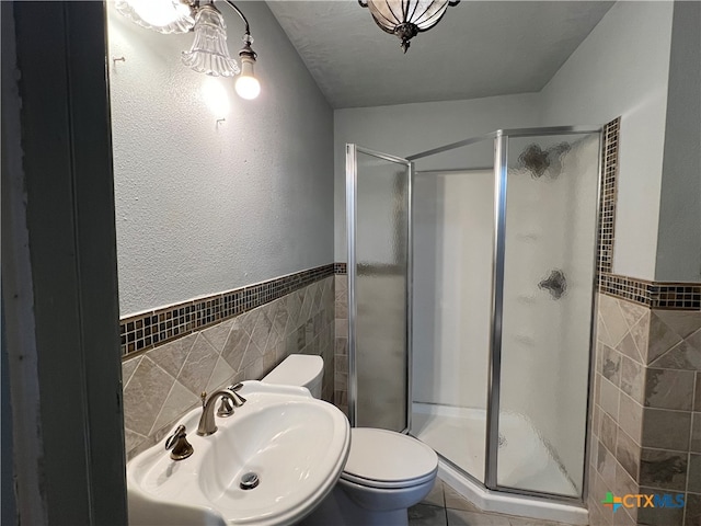 bathroom featuring sink, a textured ceiling, toilet, a shower with shower door, and tile walls