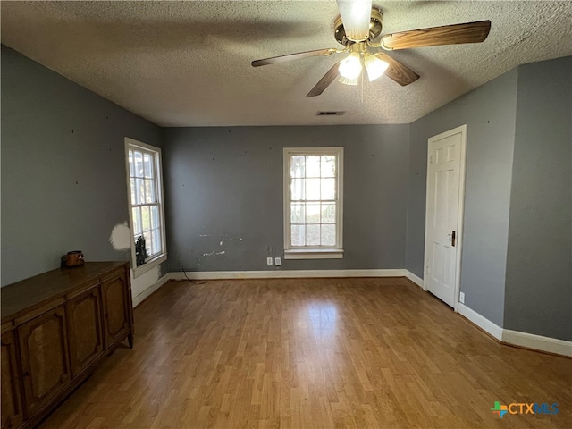 spare room with a textured ceiling, light wood-type flooring, and ceiling fan