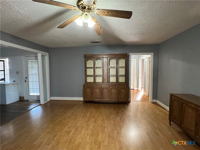 empty room featuring a textured ceiling, light hardwood / wood-style floors, and ceiling fan