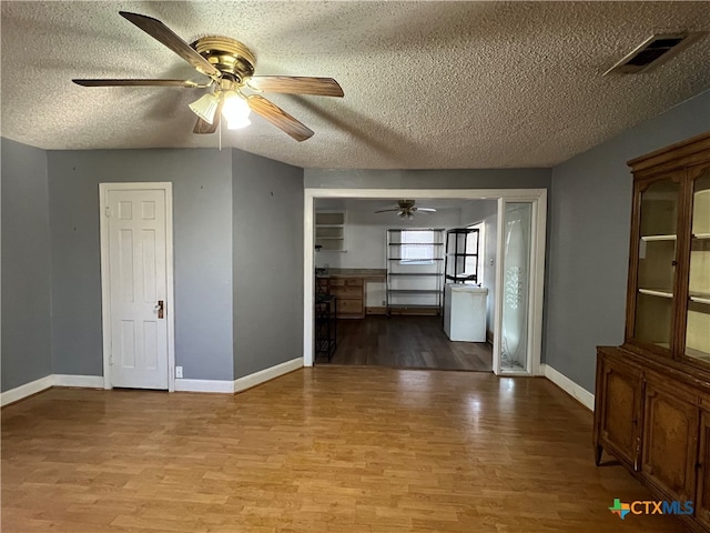 spare room with ceiling fan, light hardwood / wood-style floors, and a textured ceiling