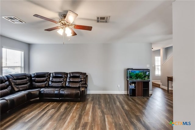 living room with a healthy amount of sunlight, dark wood-type flooring, and ceiling fan