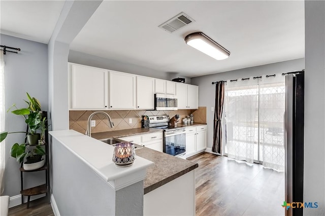 kitchen featuring sink, white cabinetry, tasteful backsplash, appliances with stainless steel finishes, and kitchen peninsula