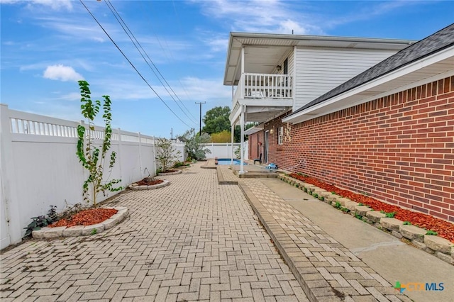 view of side of property featuring a patio area and a balcony