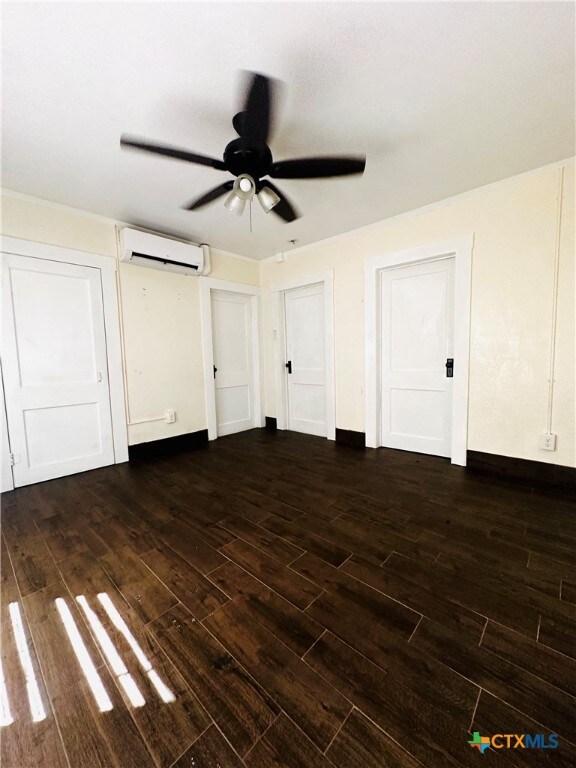 interior space with ceiling fan, dark hardwood / wood-style floors, and an AC wall unit