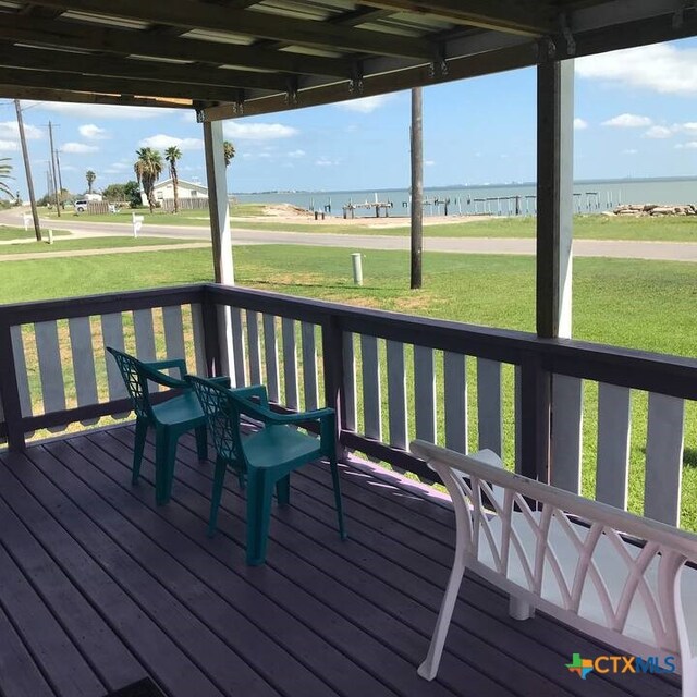 deck with a water view and a lawn