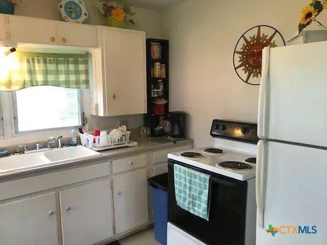 kitchen featuring white cabinets, sink, and white appliances