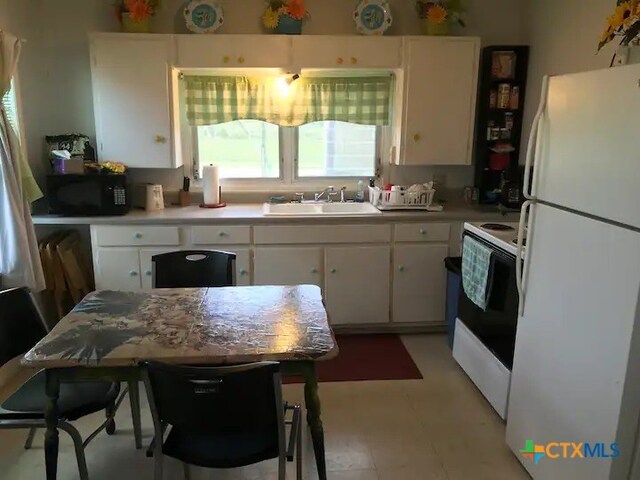 kitchen with white appliances, sink, and white cabinets