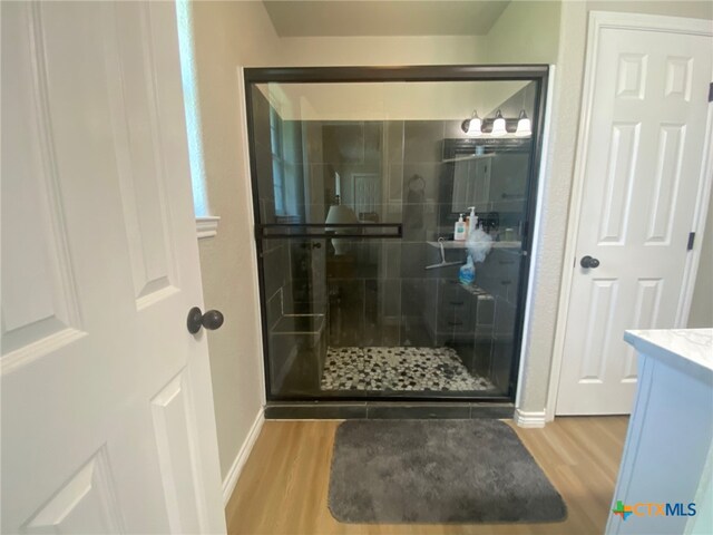 full bath with vanity, baseboards, wood finished floors, and a stall shower