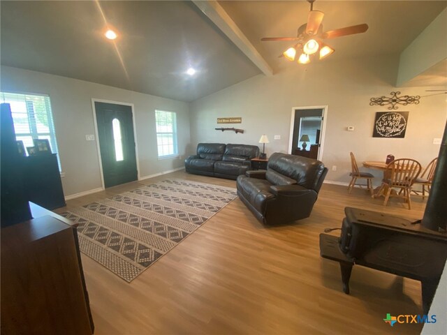 living room featuring wood finished floors, beamed ceiling, baseboards, high vaulted ceiling, and a ceiling fan