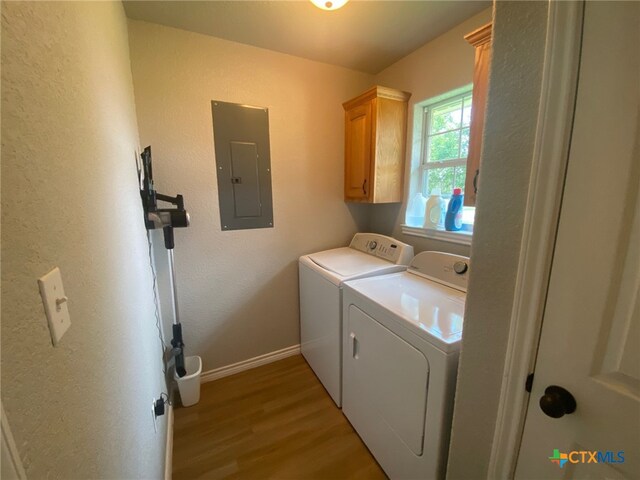 laundry area featuring electric panel, cabinet space, baseboards, light wood-style floors, and washer and dryer