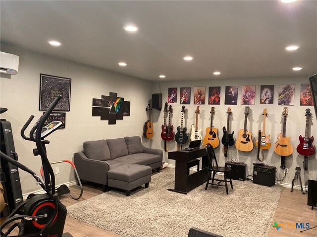 rec room featuring recessed lighting, a wall mounted air conditioner, baseboards, and wood finished floors
