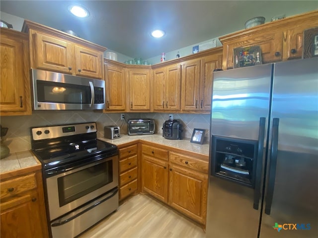 kitchen featuring backsplash, brown cabinets, and stainless steel appliances