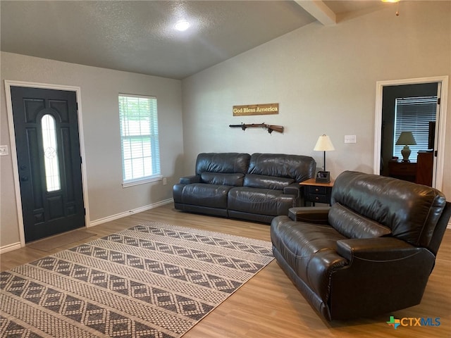 living room with vaulted ceiling with beams, a textured ceiling, baseboards, and wood finished floors