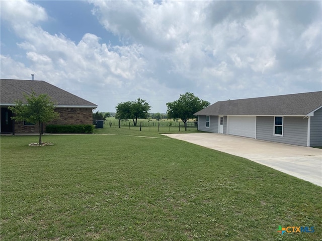 view of yard featuring fence and concrete driveway