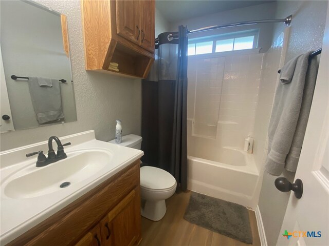 full bath featuring shower / bath combo with shower curtain, wood finished floors, toilet, and vanity